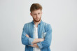 © Cookie Studio - Portrait of young handsome man with crossed arms raising up brow looking at camera over white background.