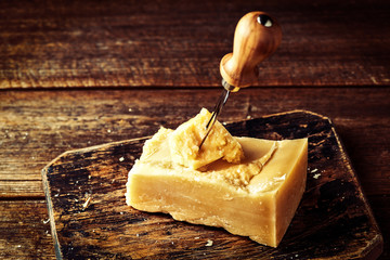 Wall Mural - Parmesan cheese on wooden board. Pieces of cheese parmesan on wooden table and cheese knife. Vintage view. Top view.