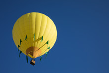 Yellow And Green Hot Air Ballon In Flight With Blue Sky Background