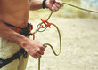 man belaying other climber through a belay device. Tubular device on locking carabiner. hands and belay device close up