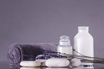 Spa. Pebbles and a towel rolled into a roll. Two jars for cream and lavender.