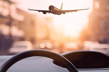 Wall Mural - Inside car view ,steering wheel and airplane on blur traffic road with colorful bokeh light abstract background.