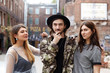 © shurkin_son - Three students best friends in fashionable street wear posing for picture, staining close to each other in urban setting, looking and smiling at camera. People, modern lifestyle and relationships