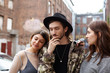 © shurkin_son - Stylish bearded guy having thoughtful look, holding hand in chin, facing dilemma as he has to choose between two gorgeous beautiful females who standing close to him, trying to attract his attention