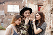 © shurkin_son - Outdoor portrait of happy fashionable young Caucasian male in hat standing outdoors between two cute young women who are in love with him. Love, dilemma, relationships, romance and dating concept