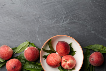 Wall Mural - Fresh peaches fruits with leaves on textured stone background, top view