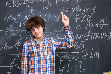 Hnadsome boy in glasses, blackboard filled with math formulas background