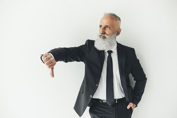 senior businessman showing thumb down on light background with angry expression