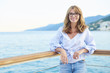 Enjoy my vacation. Portrait of an attractive middle aged woman standing outdoor in the background with the sea.