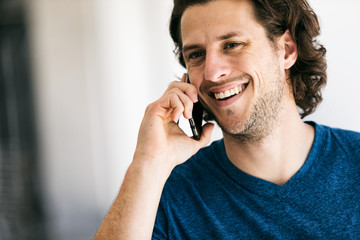 Wall Mural - Workspace: Handsome Guy Using Cell Phone In Brightly Lit Hallway