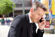 © mimagephotos - Close up portrait of serious man in suit on business call outside