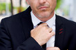 © mimagephotos - Close up serious businessman adjusting knot on tie