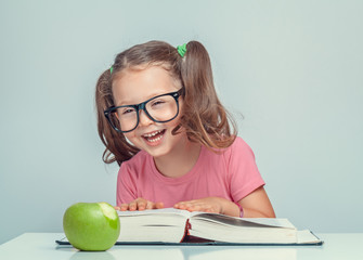 Wall Mural - beautiful cute little girl with book and green apple having fun