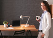 © lenets_tan - Portrait of relaxed young woman sitting at her desk holding cup of coffee. Business Woman. Workplace.