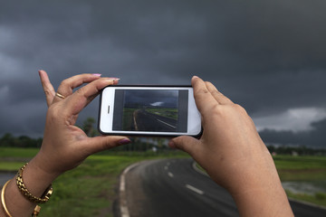 Woman taking photograph with smart phone in a overcast day