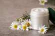  
 Natural cosmetics. A jar with cream for face and body skin care and fresh chamomile flowers on a gray background.