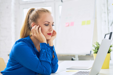 Wall Mural - Beautiful young woman sitting at desk looking at laptop on modern home office