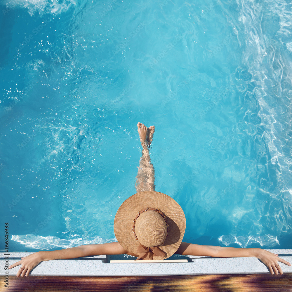 Top view of woman in straw hat relaxing in swimming pool at luxury ...