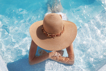 Wall Mural - Woman in beach hat enjoying in swimming pool on luxury tropical resort. Exotic Paradise. Travel, Tourism and Vacations Concept.