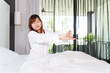 Asian woman stretching on the bed while waking up in the morning.