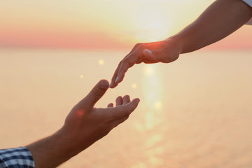 Lover boy makes an offer to his deushke on beach at sunrise (dawn). Creating a family. Creating a family. hands of the bride and groom on the background of sea close-up. Hand of support and help.