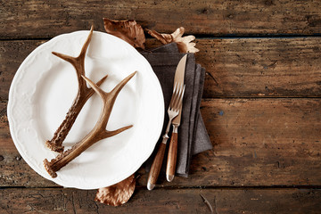 Wall Mural - deer antlers on plate with cutlery against table