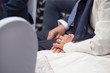 © dj_mono - Bride holding grooms hands while seated during wedding ceremony