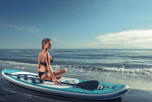 Beautiful Sporty Girl Sitting On Paddle Board At The Beach. Sunrise, Summer, Italy.