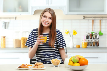 Wall Mural - Young beautiful woman having breakfast at kitchen