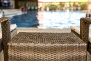 Canvas Print - Rattan table and chaise longues near modern swimming pool, closeup