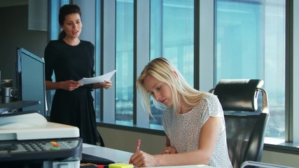 Wall Mural - Two Businesswomen Working At Desk Discuss Document