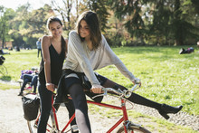 Young Friends Women On A Tandem Bicycle In The Park