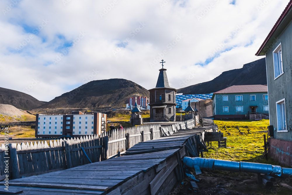 Landscape of the Russian Orthodox wooden church in the city of Barentsburg on the Spitsbergen archipelago in the summer in the Arctic - obrazy, fototapety, plakaty 