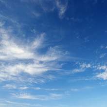 White Cirrus Clouds Against The Dark Blue Sky.