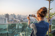 © Jovo Jovanovic/Stocksy - Woman taking a photo of Bangkok skyline in dusk