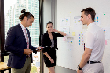 Wall Mural - three business people in modern office looking report and analyzing with talking in meeting room.