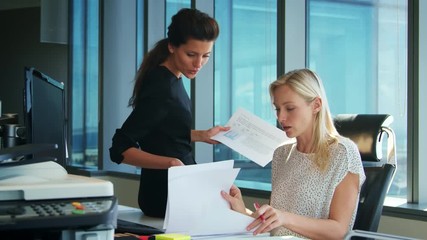 Wall Mural - Two Businesswomen Working At Desk Discuss Document