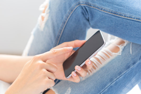 Woman checking the cell phone on the bed