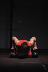 Sporty male adult doing push ups in gym