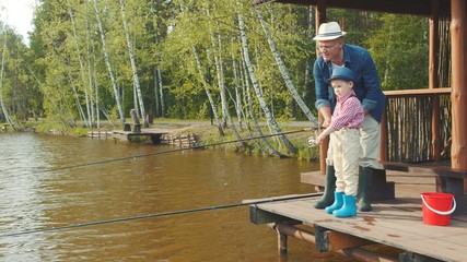 Little boy and his grandpa catching salmon on freshwater fishing at the lake