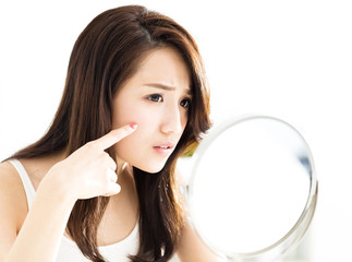 closeup of young woman looking into mirror.