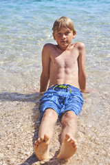 young child boy having fun in the sea on the waves and enjoying water in summer holiday