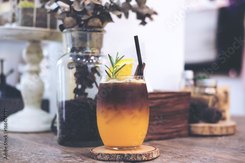Fotomural Closeup image of a glass of orange cold brew coffee on wooden table
