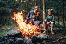 Father And Son Roast Marshmallow On Campfire