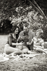 Sticker - Cheerful family sitting on the grass during un picnic in a park