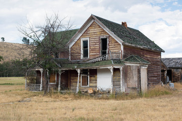 Old abandoned wooden farm house on prairie setting with light, sky background