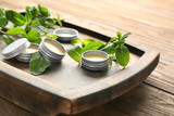 Fototapeta  - Containers with lemon balm salve and leaves on table