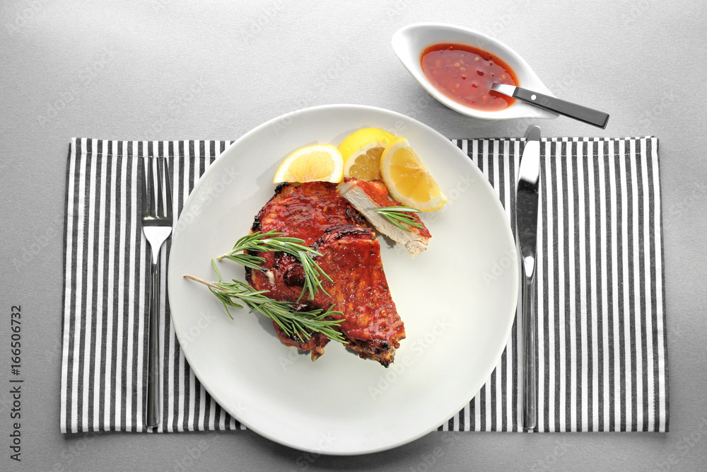 Plate with delicious pork ribs on table