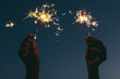 © BONNINSTUDIO/Stocksy - Hands of woman holding sparklers at night.