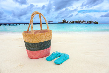 Canvas Print - Bag and flip-flops on sea beach. Summer vacation concept